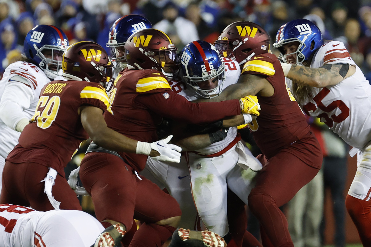 Washington Commanders defensive tackles Jonathan Allen (93) and Daron Payne (94) wrap up New York Giants running back Saquon Barkley during the third quarter at FedExField in 2022.