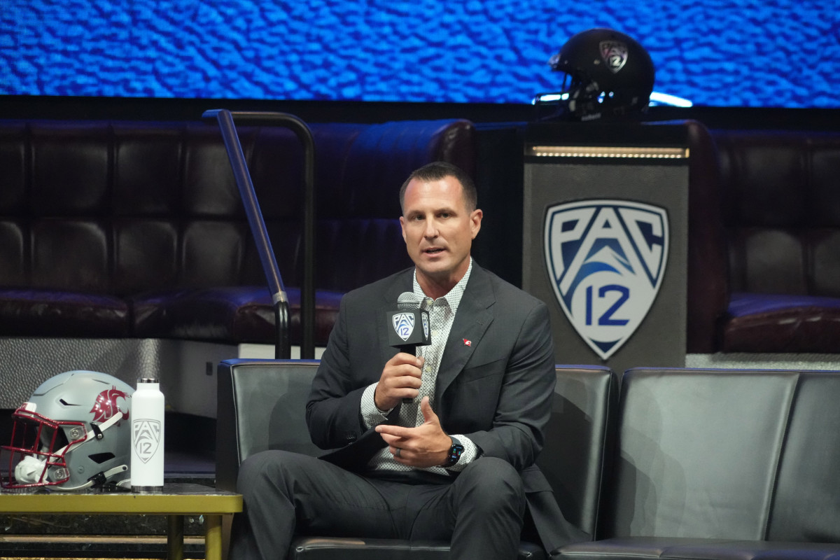 Washington State head coach Jake Dickert sits and holds a Pac-12 themed microphone