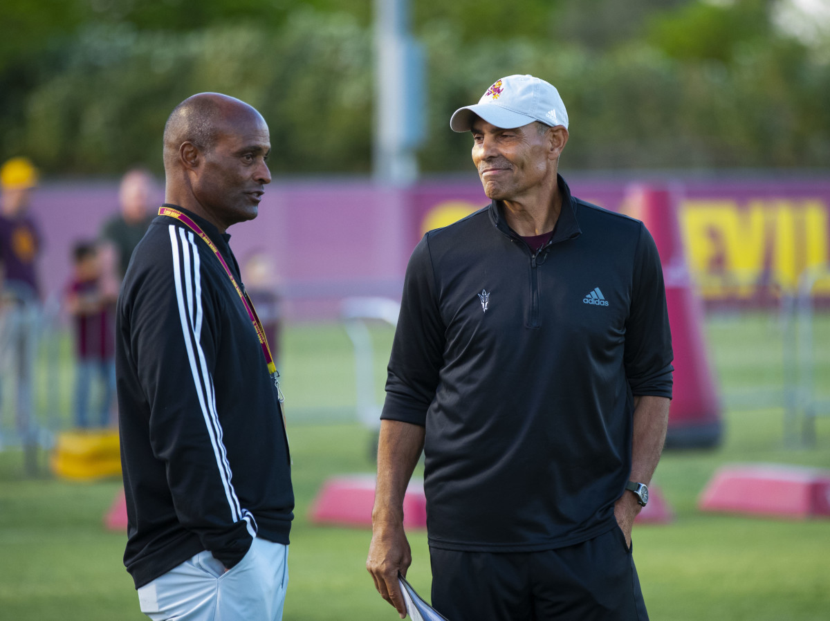Ray Anderson (left) has his hands in his pockets as he talks to Herm Edwards (right)