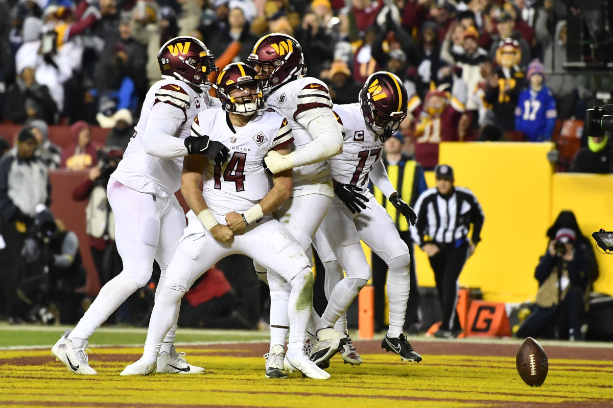 Sam Howell flexes his arms down in celebration as teammates cling to him