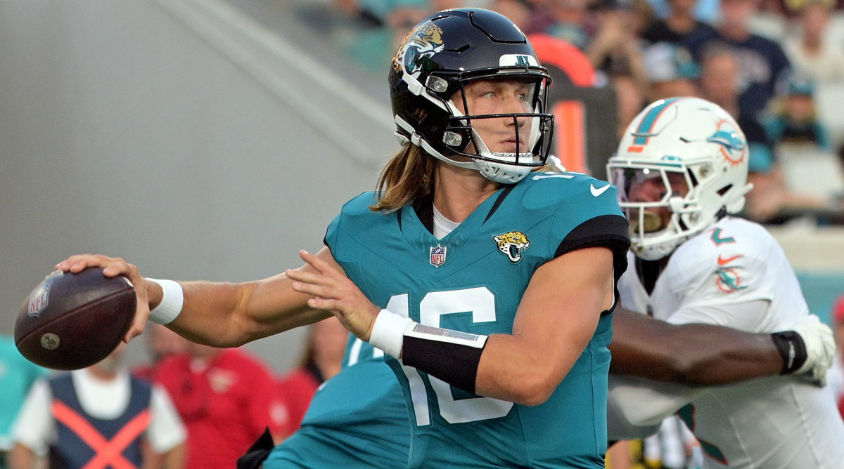Trevor Lawrence throws the ball as a Dolphins defender is blocked by his O-line