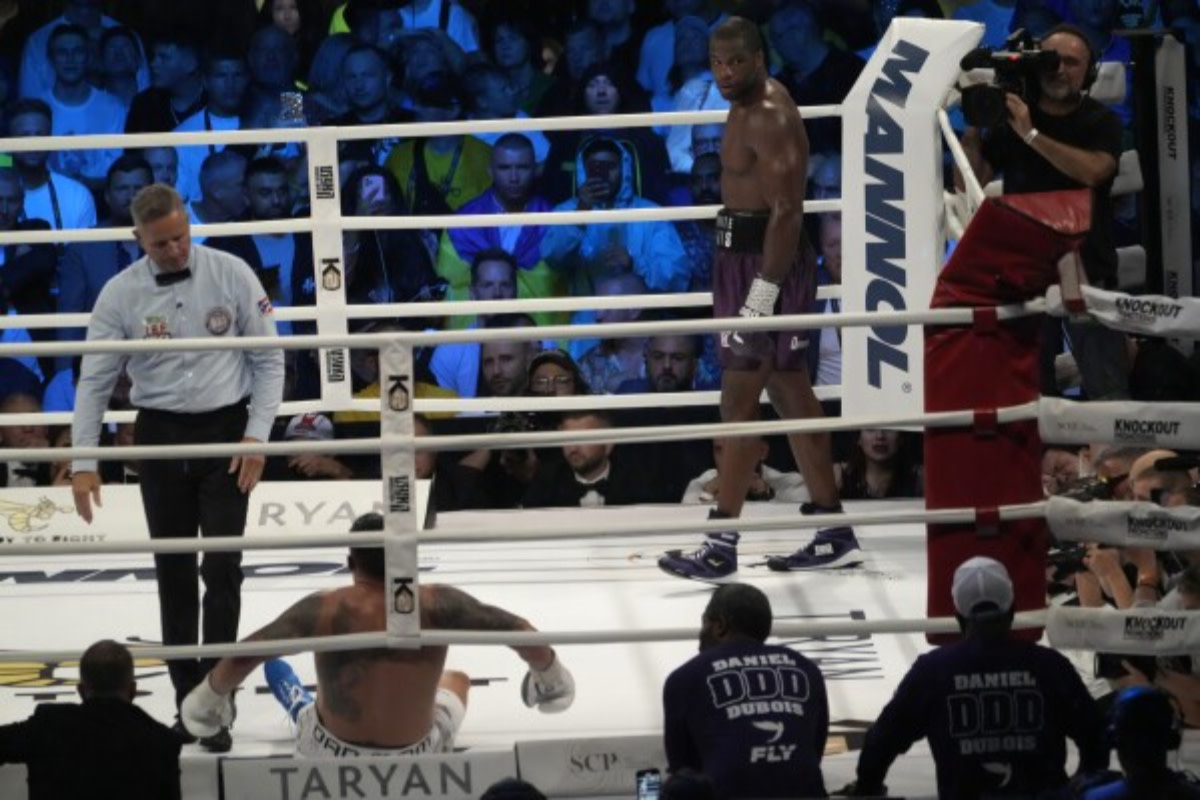 Oleksandr Usyk recovers after being dropped by a low blow from Daniel Dubois in their heavyweight boxing title fight.