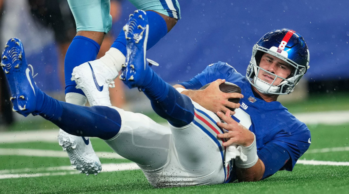 Daniel Jones on his butt, with his feet up in the air, on a rainy night