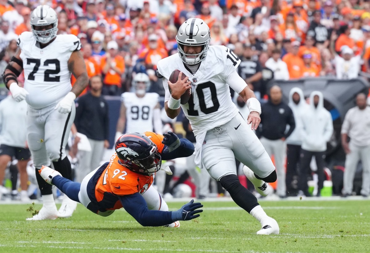 Las Vegas Raiders quarterback Jimmy Garoppolo (10) scrambles past Denver Broncos defensive tackle Jonathan Harris (92) in the first quarter at Empower Field at Mile High.