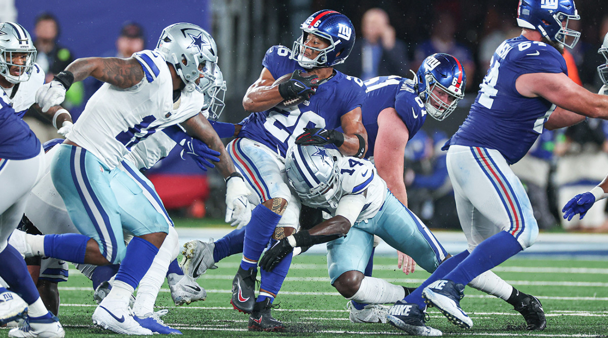 Giants running back Saquon Barkley (26) is tackled by Cowboys safety Markquese Bell (14) during the first half at MetLife Stadium.