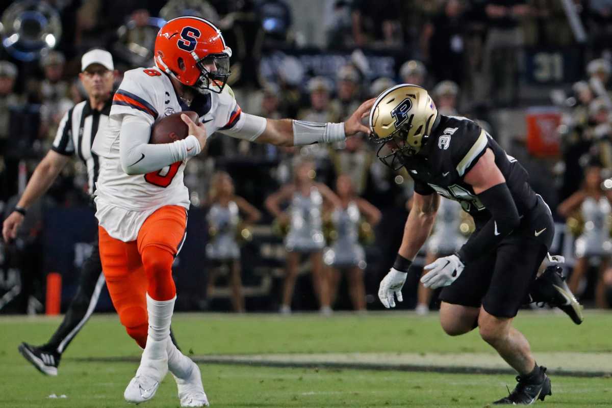 Garrett Shrader puts his arm out to block a Purdue player running toward him