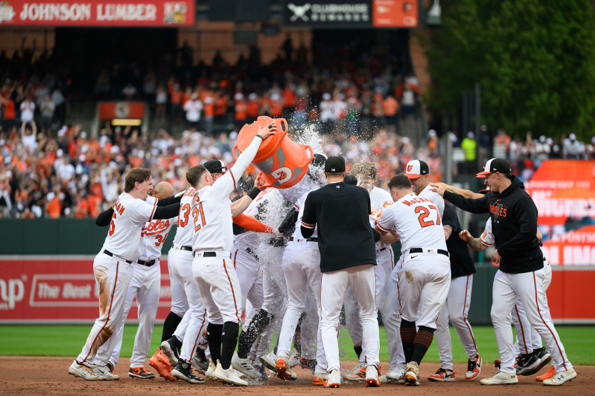 Orioles players lift a gatorade jug and dump it on the huddle of the team