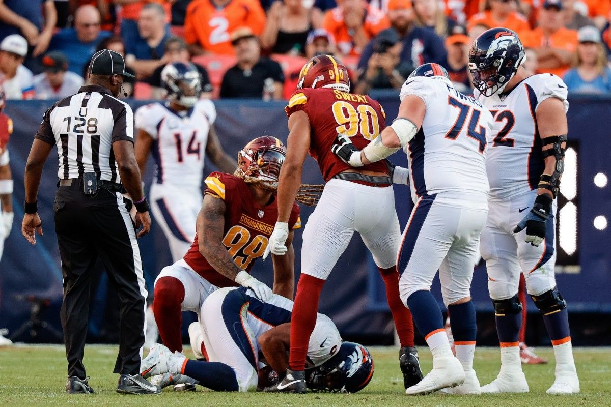 Washington Commanders defensive end Chase Young (99) reacts with defensive end Montez Sweat (90) after they sacked Denver Broncos quarterback Russell Wilson (3) as umpire Ramon George (128) and guard Ben Powers (74) and offensive tackle Garett Bolles (72) look on in the fourth quarter at Empower Field at Mile High.