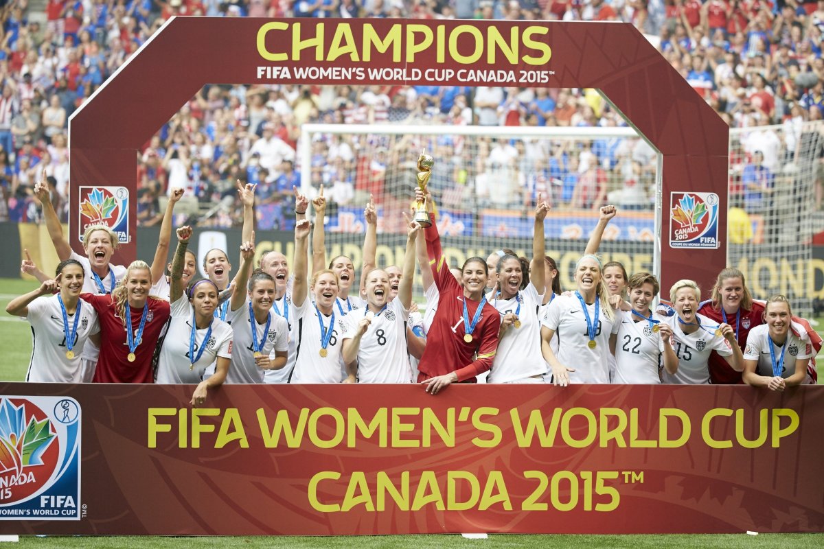 USA goalie Hope Solo holds up the World Cup trophy with her USWNT teammates celebrating their 2015 World Cup title.