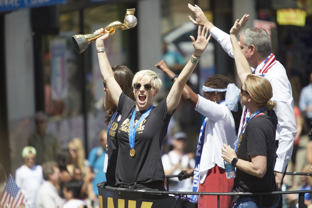 Megan Rapinoe holds up the World Cup trophy in front of New York City mayor Bill de Blasio on float during the USWNT's Victory Parade in 2019.