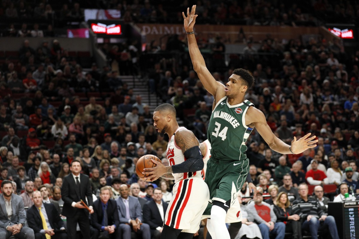 Portland Trail Blazers point guard Damian Lillard (0) grabs a rebound ahead of Milwaukee Bucks power forward Giannis Antetokounmpo (34