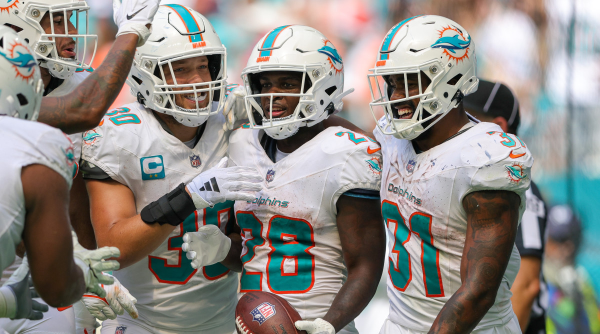 Dolphins running back De'Von Achane, center, celebrates his touchdown with fellow tailback Raheem Mostert, right, and fullback Alec Ingold, left, against the Denver Broncos.
