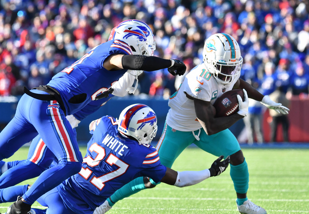 Two Bills defenders attempt to tackle Miami's Tyreek Hill.