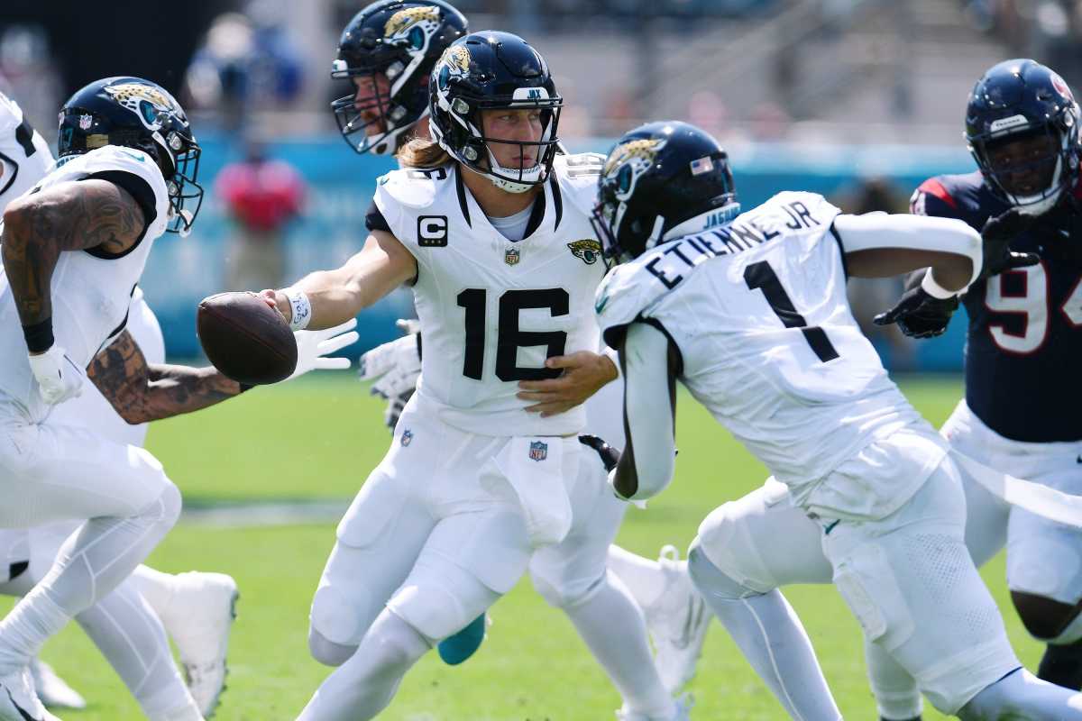 Trevor Lawrence passes off the ball to a running back as other Jaguars players run by him