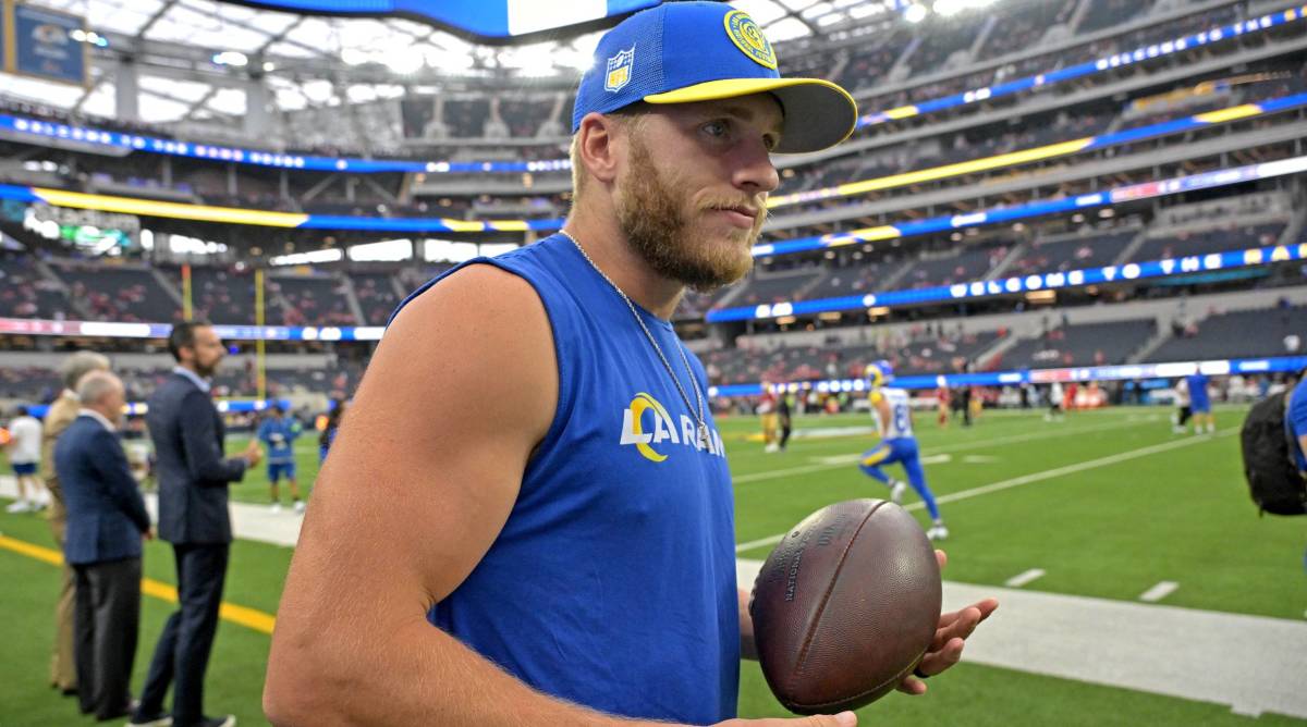 Rams wide receiver holds a football on the sidelines while inactive before a game.