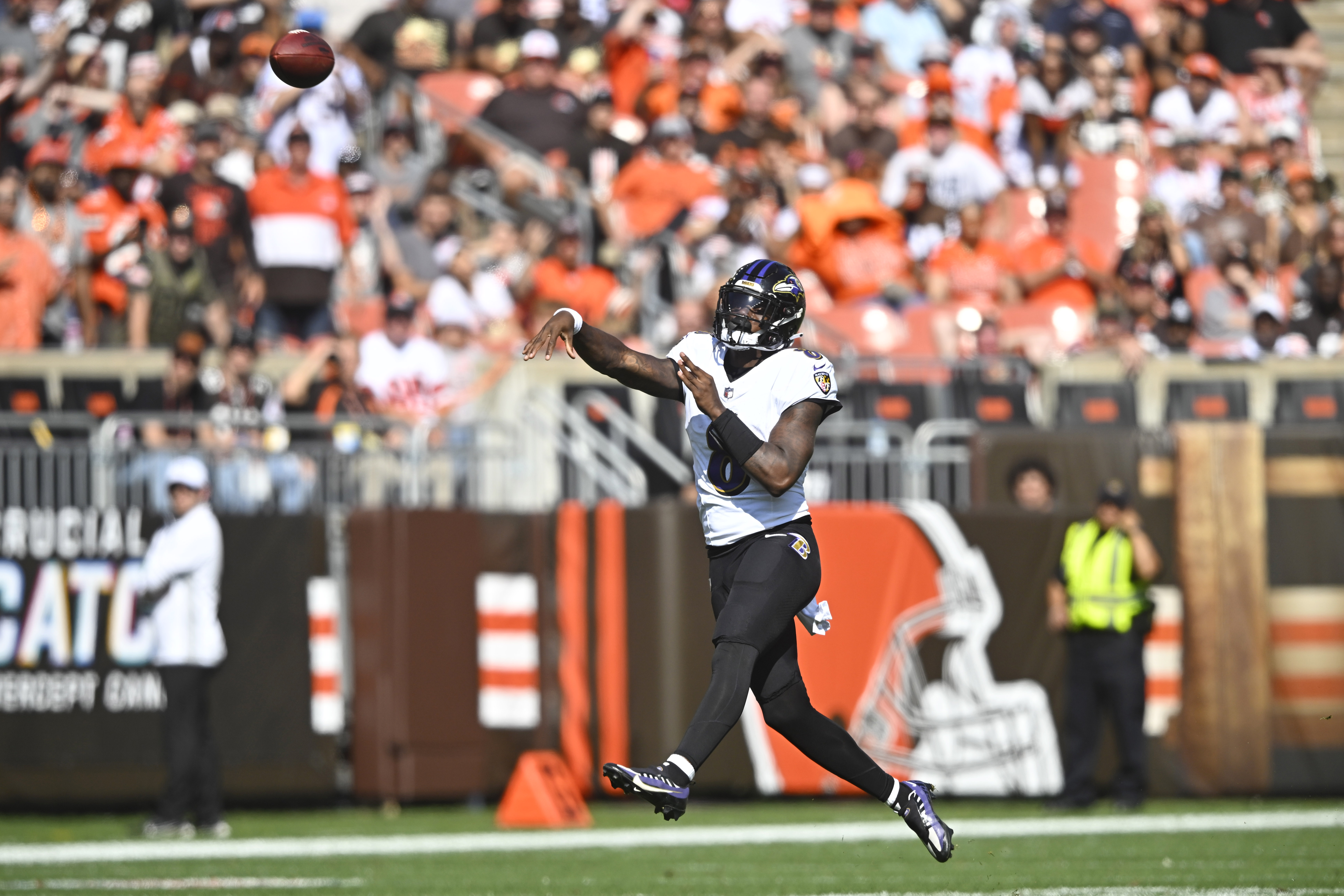 Lamar Jackson throws the ball with a crowd of Browns fans in the stadium seats behind him
