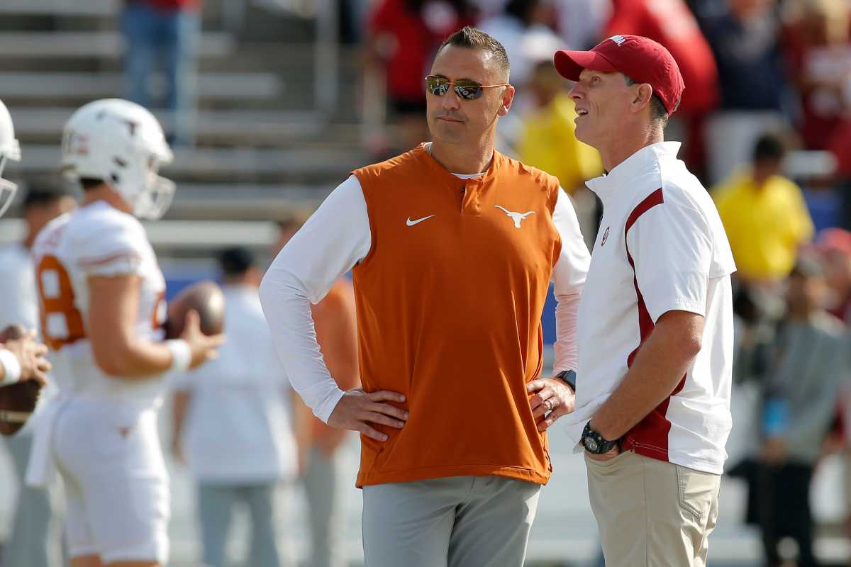 Steve Sarkisan stands with his hands on his hips talking to Brent Venables, who has his hands in his pockets