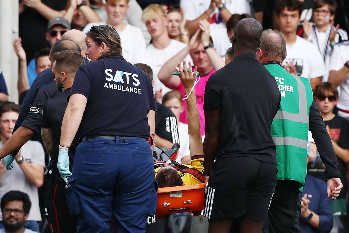 Sheffield United player Chris Basham pictured (center) raising his right arm as he is removed from the field on a stretcher after breaking his left ankle during an EPL game against Fulham in October 2023