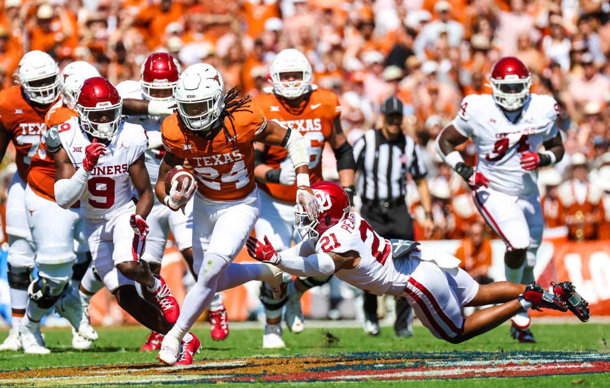 Texas Longhorns running back Jonathon Brooks evades a tackle against a pair of Oklahoma Sooners defenders in the Red River Showdown at the Cotton Bowl in Dallas, Texas. 