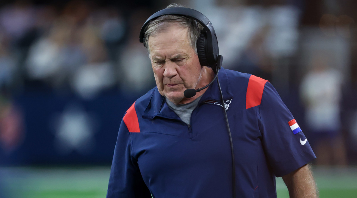 Bill Belichick looks down walking with a headset on