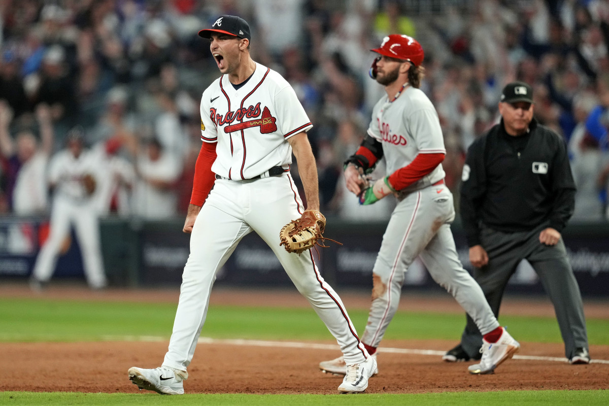 Austin Riley yells in celebration as Bryce Harper walks off the field behind him