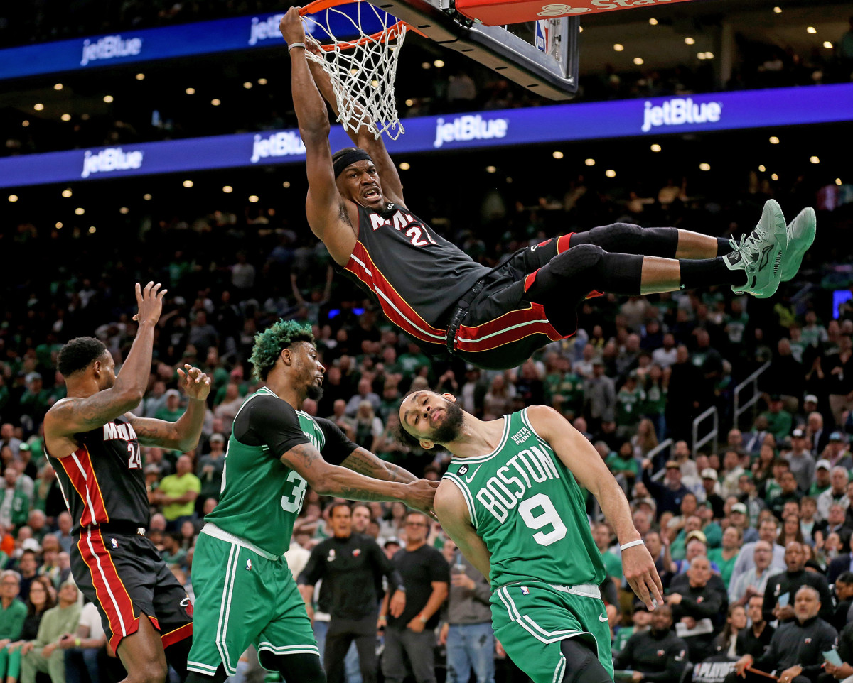 Jimmy Butler holds onto the rim after dunking against the Celtics in the NBA playoffs.