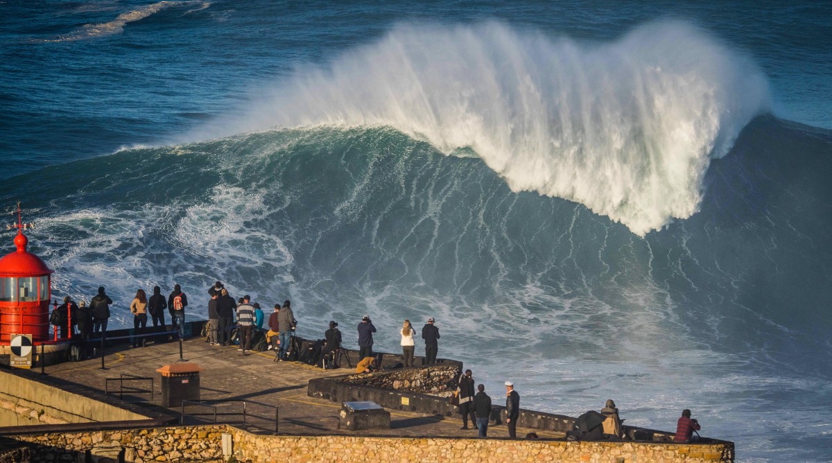A crowd gathers at the Nazaré lighthouse to watch the surfing.
