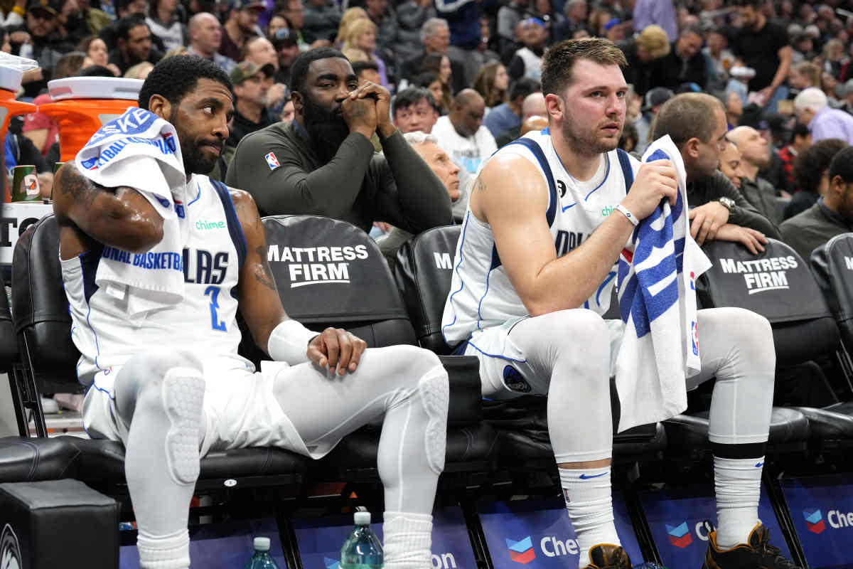 Luka Doncic and Kyrie Irving sit on the bench during a timeout against the Sacramento Kings.