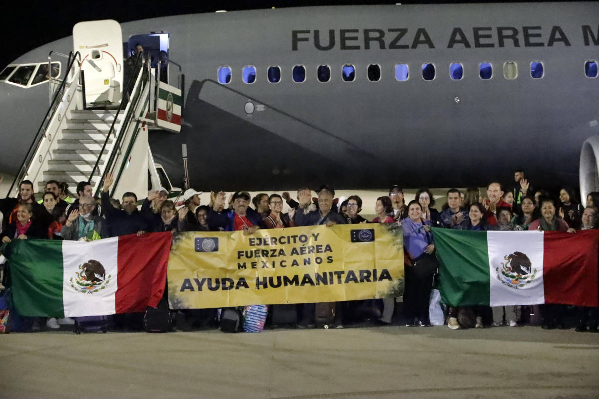 Mexicanos repatriados de Israel sostienen bandera de México y manta