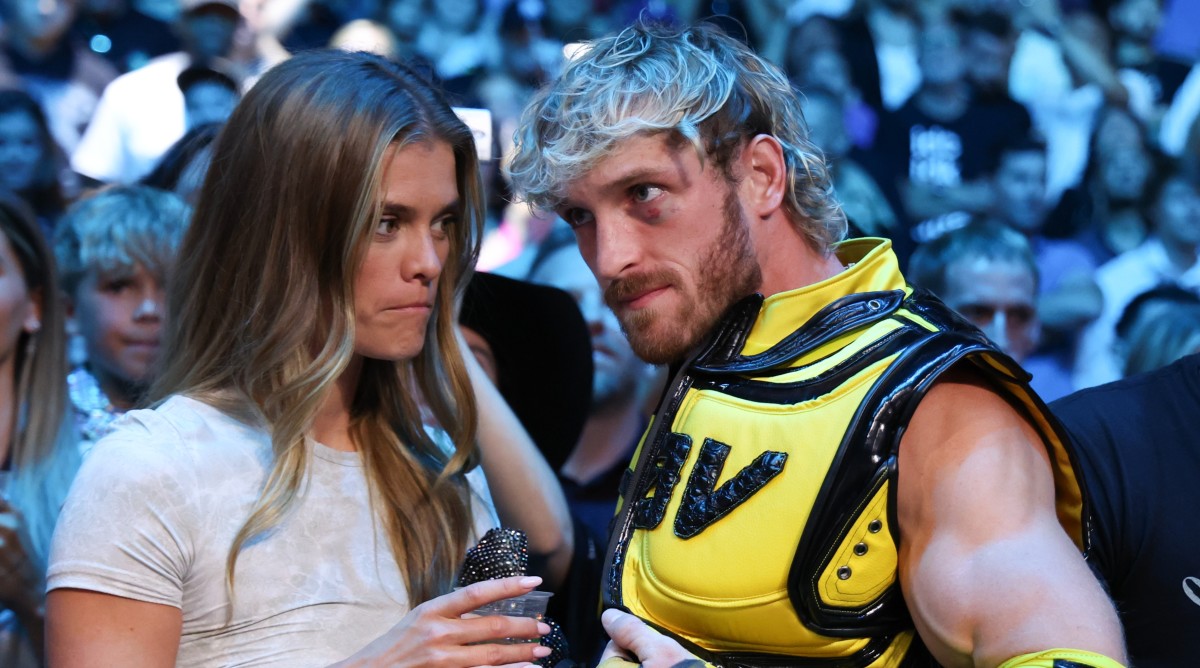 Wrestler and boxer Logan Paul stands alongside fiancé Nina Agdal in the crowd at a boxing match.