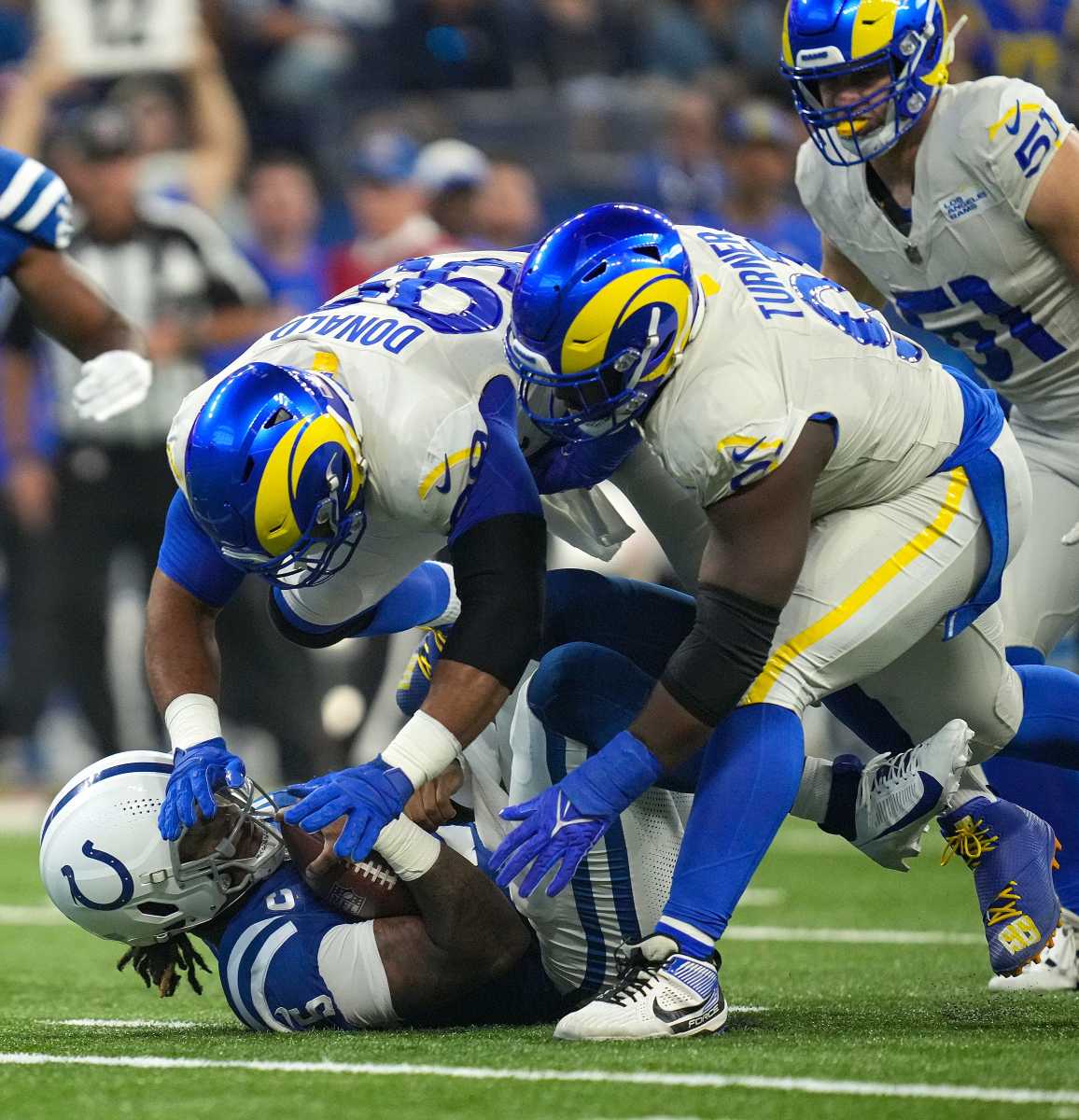 Indianapolis Colts quarterback Anthony Richardson (5) falls down and is tackled by Los Angeles Rams defensive tackle Aaron Donald (99) and defensive tackle Kobie Turner (91) during the first half of the game Sunday, Oct. 1, 2023, at Lucas Oil Stadium in Indianapolis.