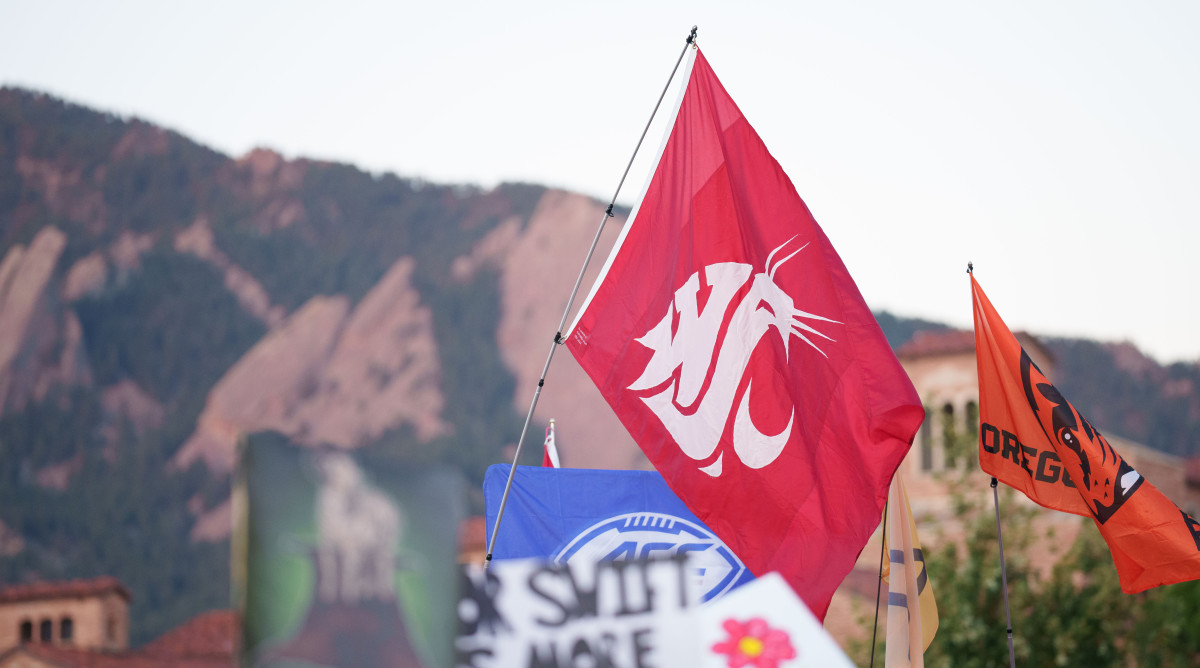 Fans hold a Washington State University flag and an Oregon State flag on the set of ESPN College GameDay in Boulder, Colorado.