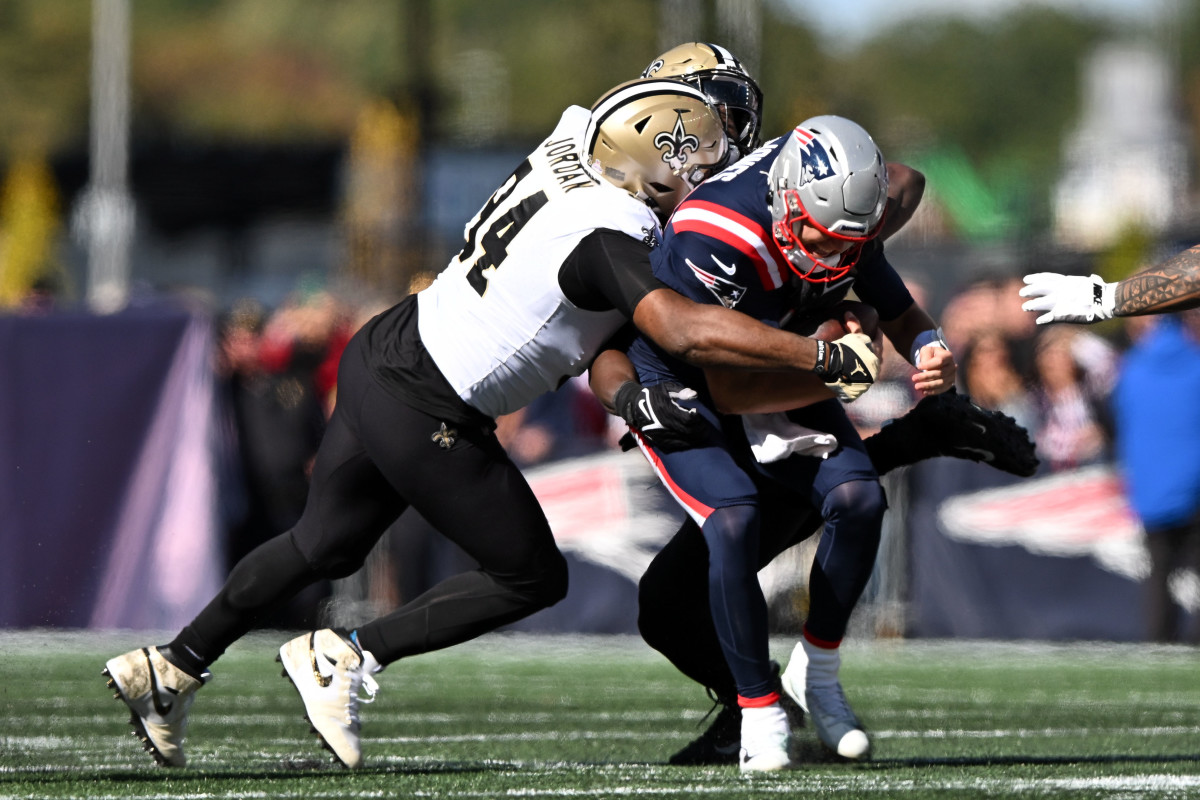 New England Patriots quarterback Mac Jones (10) is sacked by New Orleans Saints defensive end Tanoh Kpassagnon (92) and defensive end Cameron Jordan (94) during the first half at Gillette Stadium.