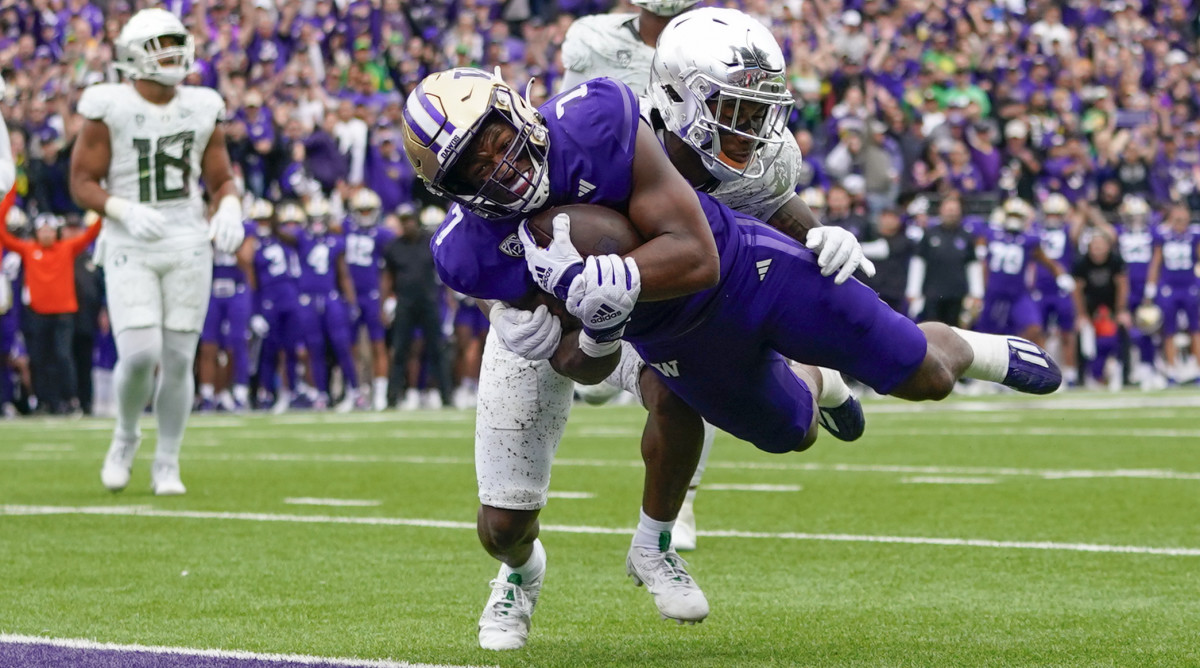 Washington running back Dillon Johnson jumps into the end zone in front of Oregon defensive back Steve Stephens IV for a touchdown
