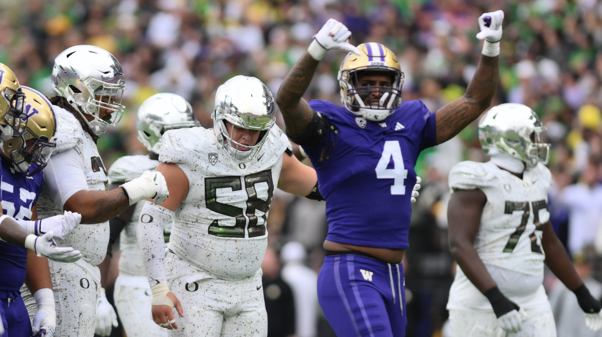 Washington Huskies player gestures thumbs-down while Oregon player looks down in the background