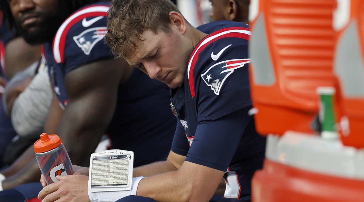 Patriots quarterback Mac Jones, right, is seated on the bench after he was pulled during the second half against the Saints.