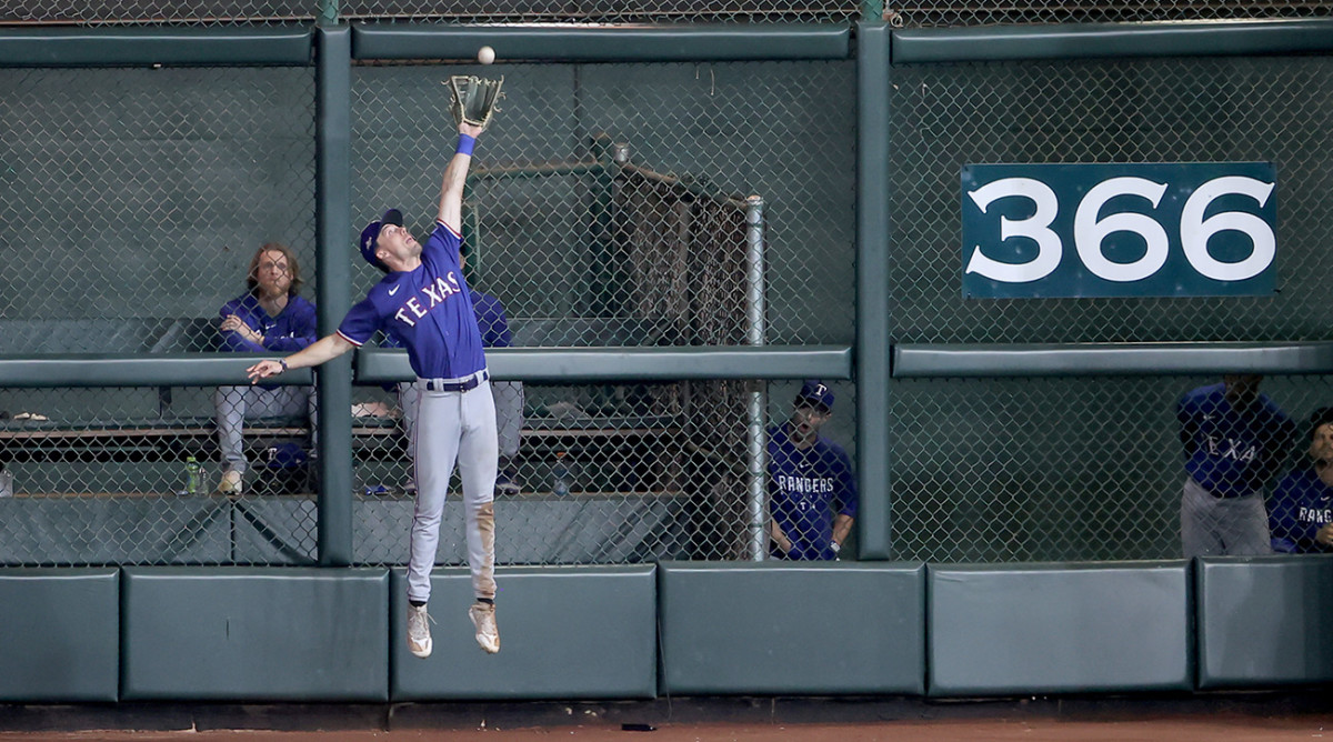 Rangers’ Evan Carter makes a leaping grab at the wall vs. Astros.