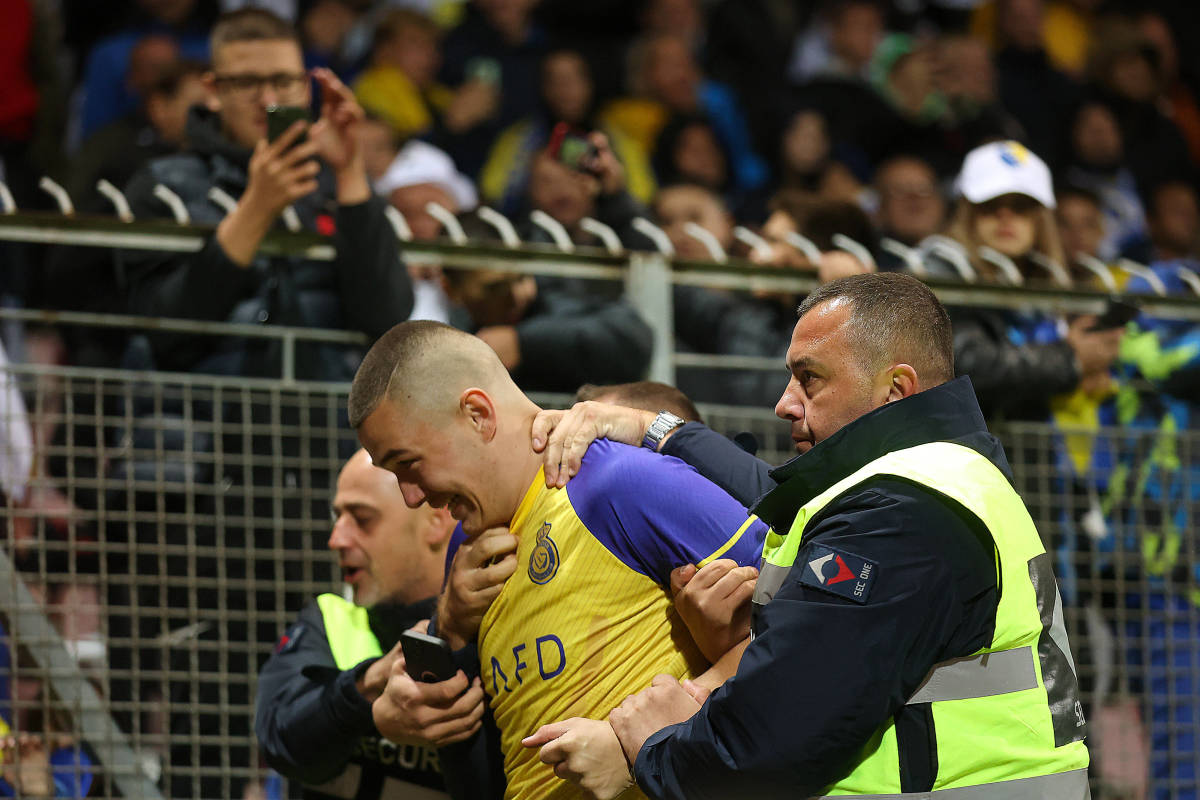 A pitch invader wearing an Al Nassr jersey pictured being led away by security staff after trying to take a selfie with Cristiano Ronaldo during Portugal's 5-0 win over Bosnia and Herzegovina in Zenica in October 2023