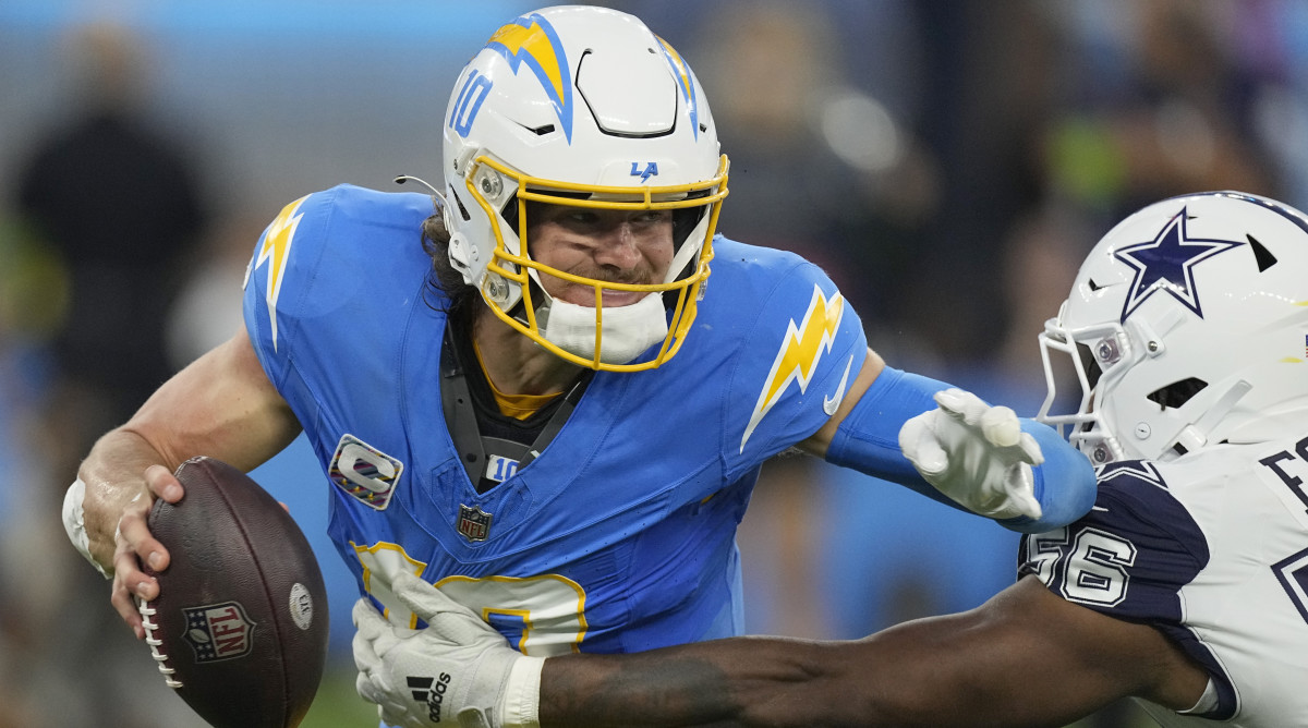 Chargers quarterback Justin Herbert attempts to evade a tackle by Cowboys defensive end Dante Fowler Jr.