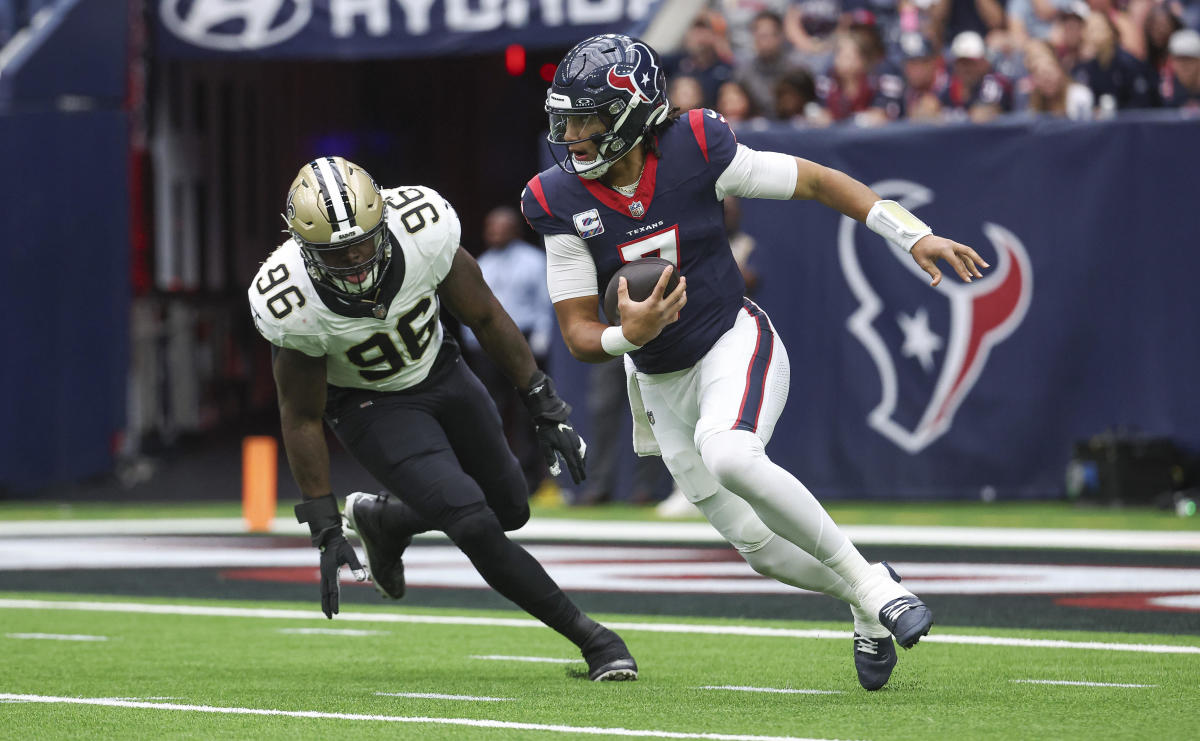 C.J. Stroud runs with the ball in one hand as a Saints defender chases after him