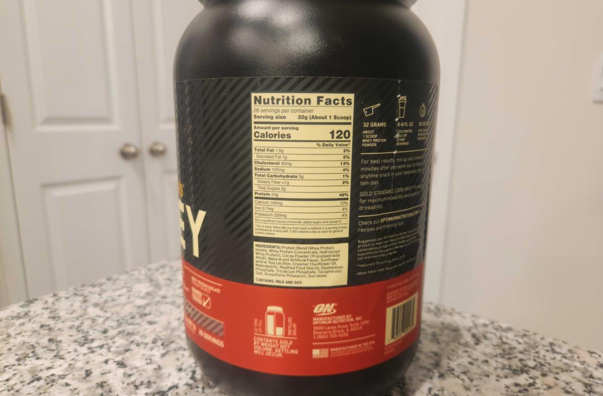 The Nutrition Facts label of a tub of Optimum Nutrition 100% Whey protein powder on a granite countertop