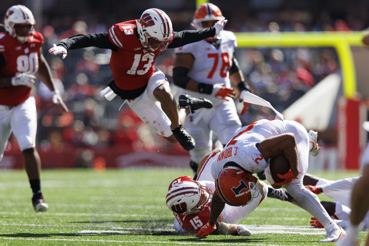 Oct 1, 2022; Madison, Wisconsin, USA; Illinois Fighting Illini running back Chase Brown (2) is tackled with the football as Illinois Fighting Illini defensive back Matthew Bailey (13) leaps over the play during the third quarter at Camp Randall Stadium. Mandatory Credit: Jeff Hanisch-USA TODAY Sports