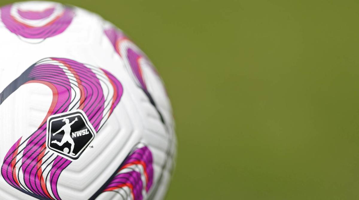 A soccer ball with an NWSL logo on it sits on a field.
