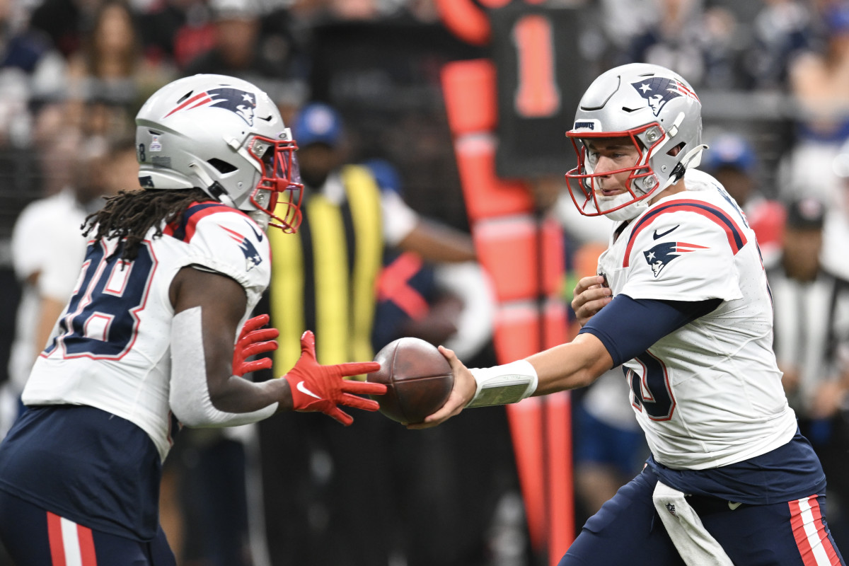 New England Patriots quarterback Mac Jones (10) hands the ball off to New England Patriots running back Rhamondre Stevenson (38) in the first quarter at Allegiant Stadium.