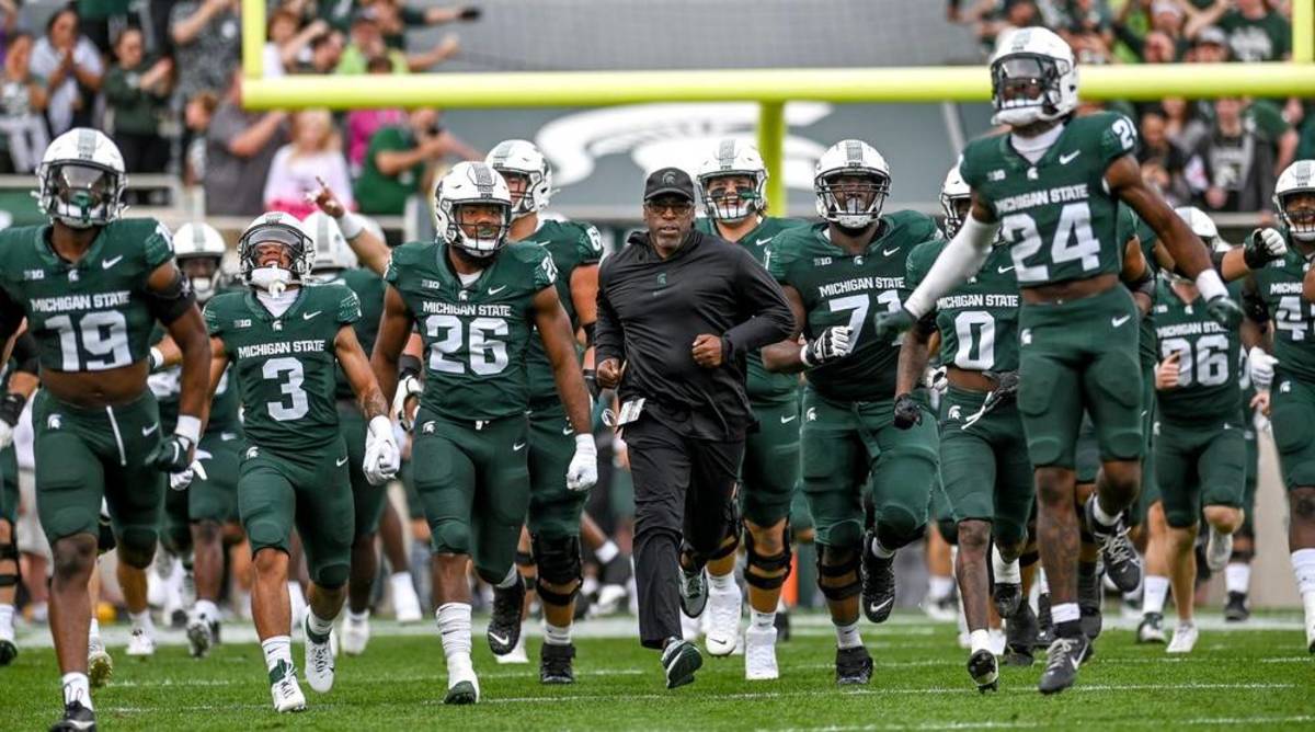 The Michigan State football teams runs onto the field before a game.