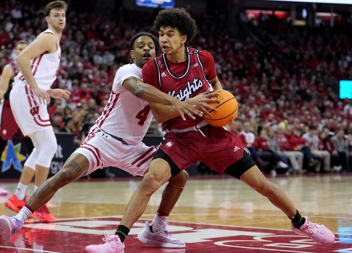 Derek Simpson holds the ball with two hands as a Wisconsin defender reaches for it