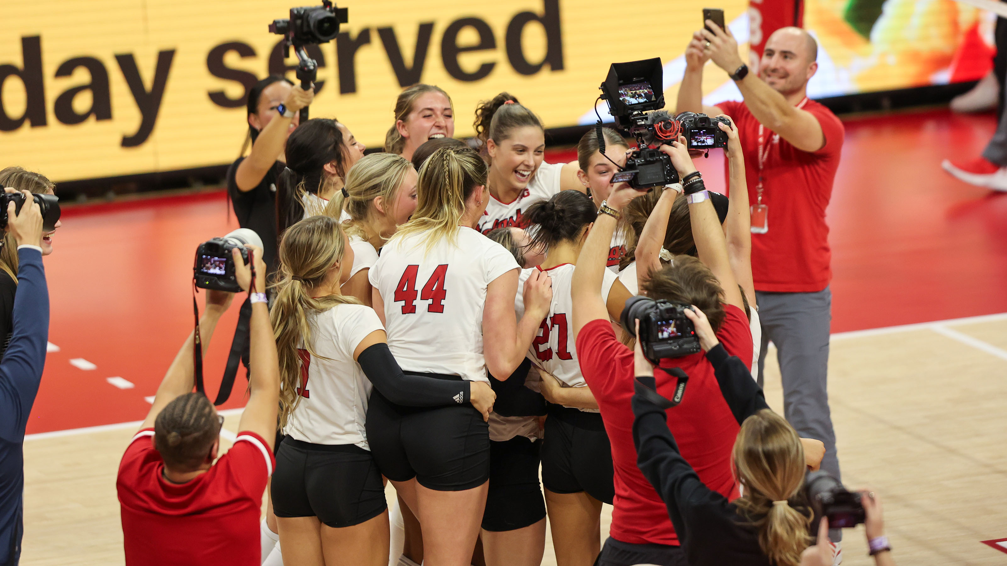 Nebraska volleyball players celebrate on the court after upsetting top-ranked Wisconsin (Oct. 21, 2023)