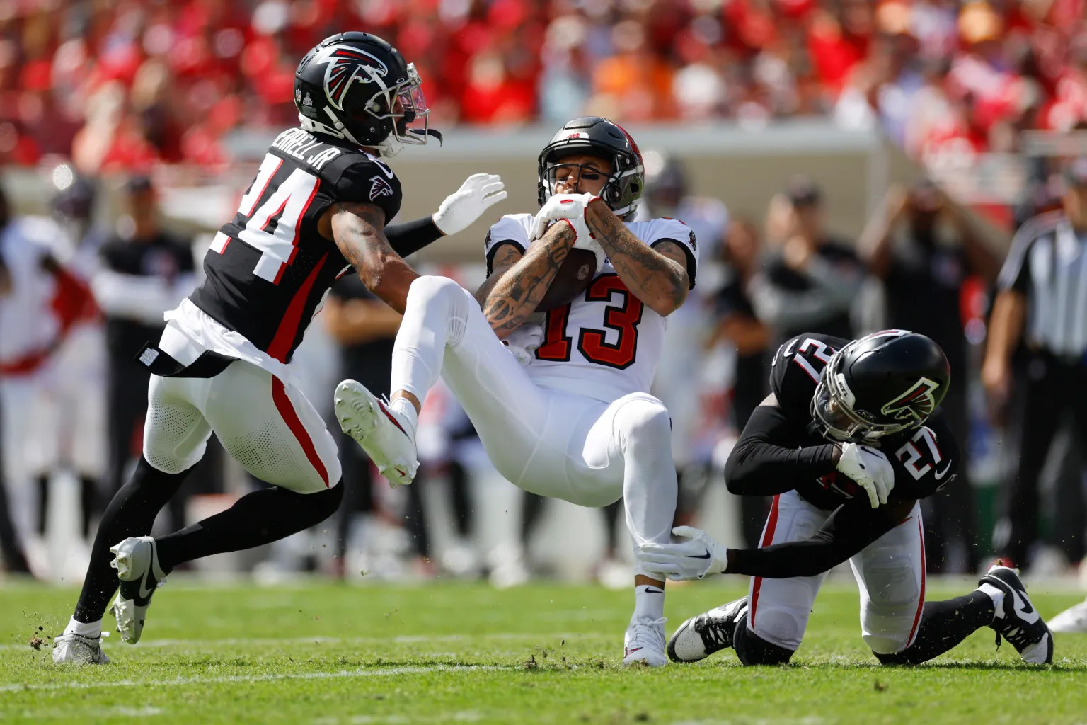 Buccaneers WR Mike Evans hauls in a catch between two Falcons defenders.