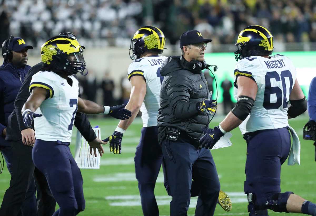 Jim Harbaugh high fives Michigan players as they run off the field