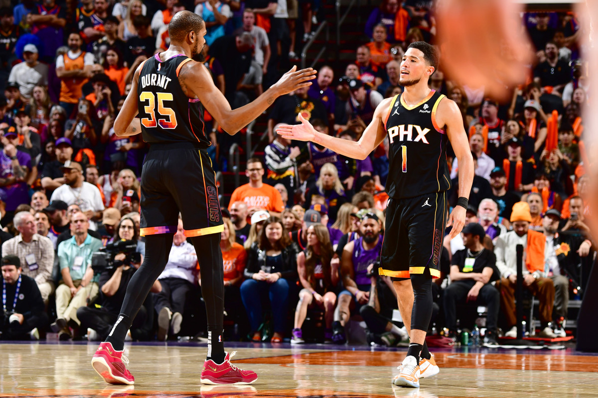 Kevin Durant and Devin Booker high five after a play in a Phoenix Suns game.